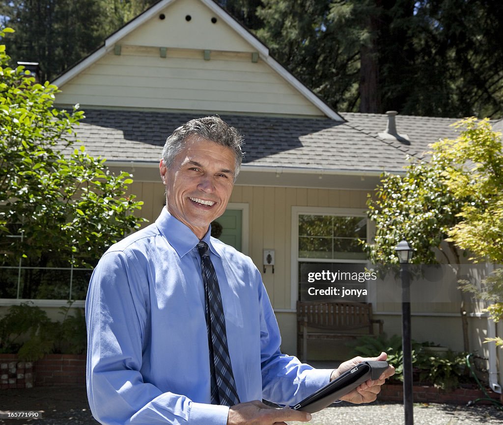 Real estate agent smiling in front of a house