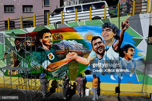 Local artists paint a mural depicting Argentine players Lionel Messi , Mario Kempes and late Diego Maradona and Bolivia's Marco Antonio Etcheverry,...