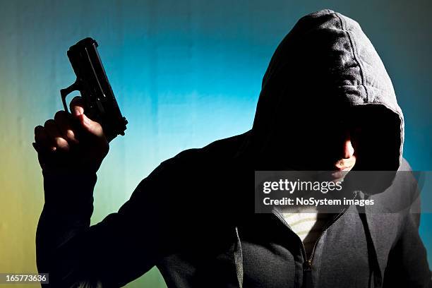 man in hood with revolver - hooligan stock pictures, royalty-free photos & images