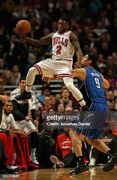 Nate Robinson of the Chicago Bulls leaps to save the ball from going out of bounds over Nikola Vucevic of the Orlando Magic at the United Center on...