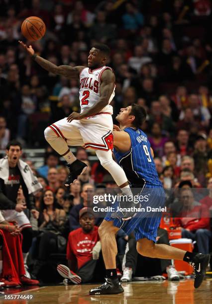 Nate Robinson of the Chicago Bulls leaps to save the ball from going out of bounds over Nikola Vucevic of the Orlando Magic at the United Center on...