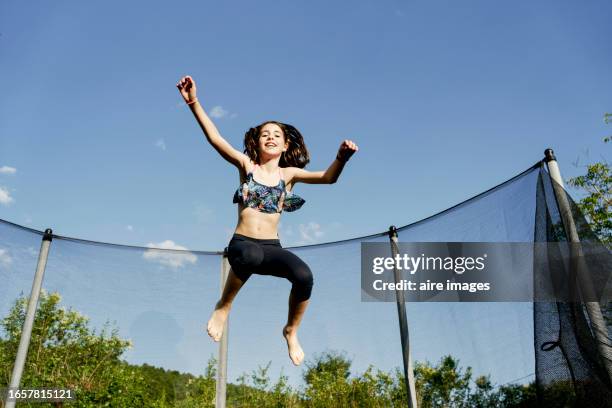 a girl posing for the camera jumping on a trampoline - jump shot stock pictures, royalty-free photos & images