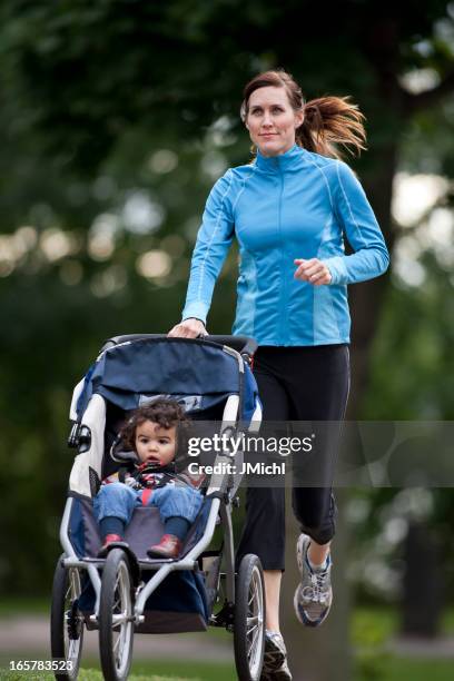 jogger with baby jogger running on a paved trail. - three wheeled pushchair stock pictures, royalty-free photos & images