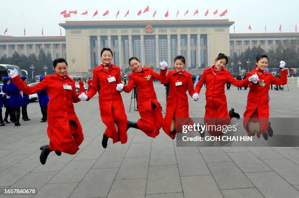 Chinese hostesses pose for a photo on Tiananmen Square during the opening session of the National People's Congress at the Great Hall of the People...