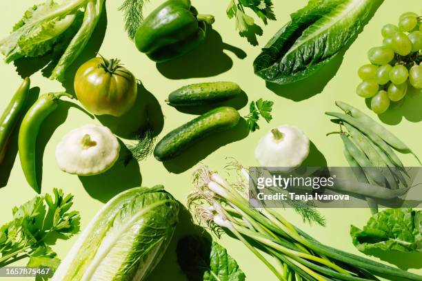 fresh green organic vegetables and fruits on green background. healthy food, diet and detox concept. flat lay, top view - estudio de mercado fotografías e imágenes de stock
