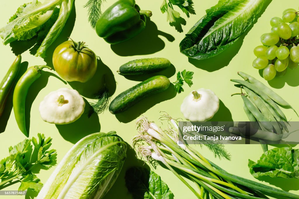 Fresh green organic vegetables and fruits on green background. Healthy food, diet and detox concept. Flat lay, top view