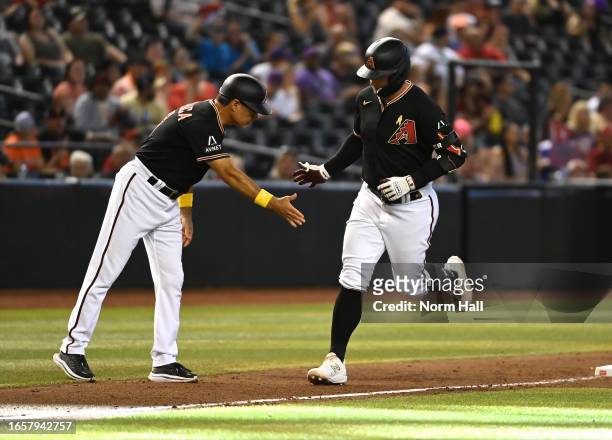 Christian Walker of the Arizona Diamondbacks celebrates with third base coach Tony Perezchica after hitting a solo home run against the Baltimore...