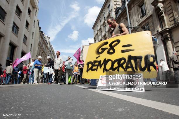 Protestor holds a placard reading "G8 = Democratur" a contraction of French words "democratie" and "dictature" as he takes part in a demonstration,...