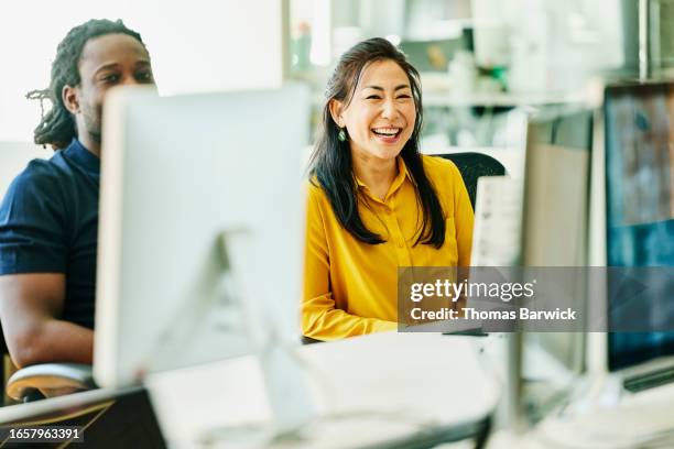 medium wide shot colleagues working on computers in start up office - business finance and industry stock pictures, royalty-free photos & images