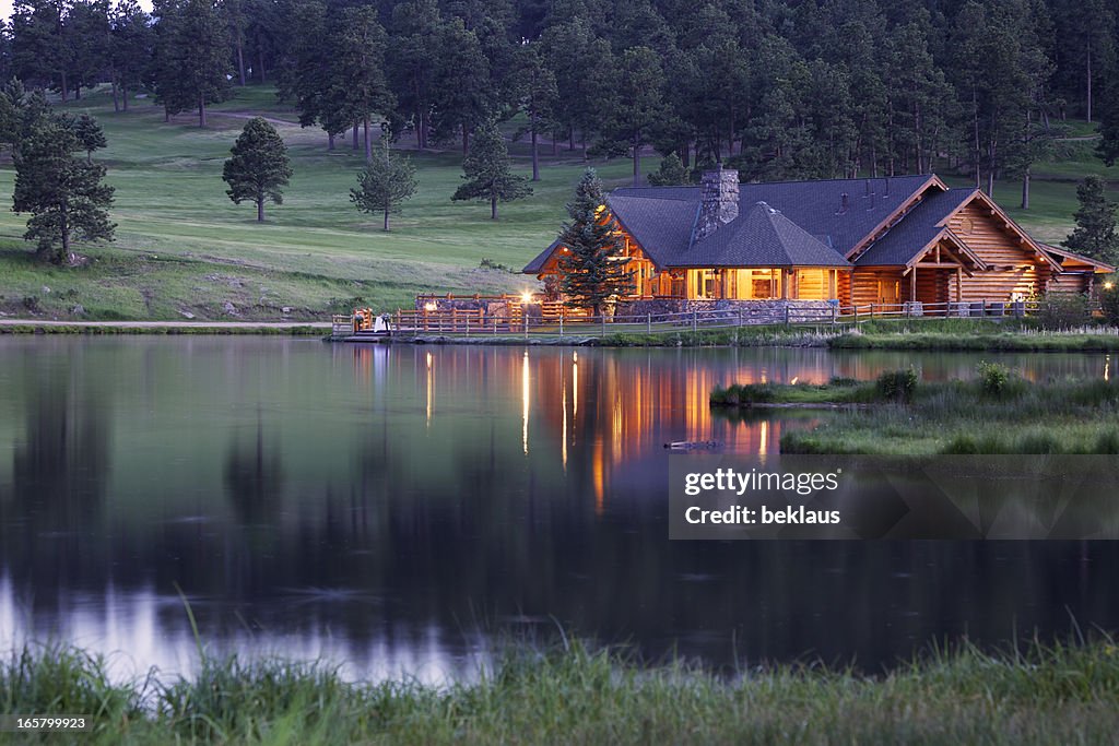 Mountain Lodge que refleja en el lago al atardecer