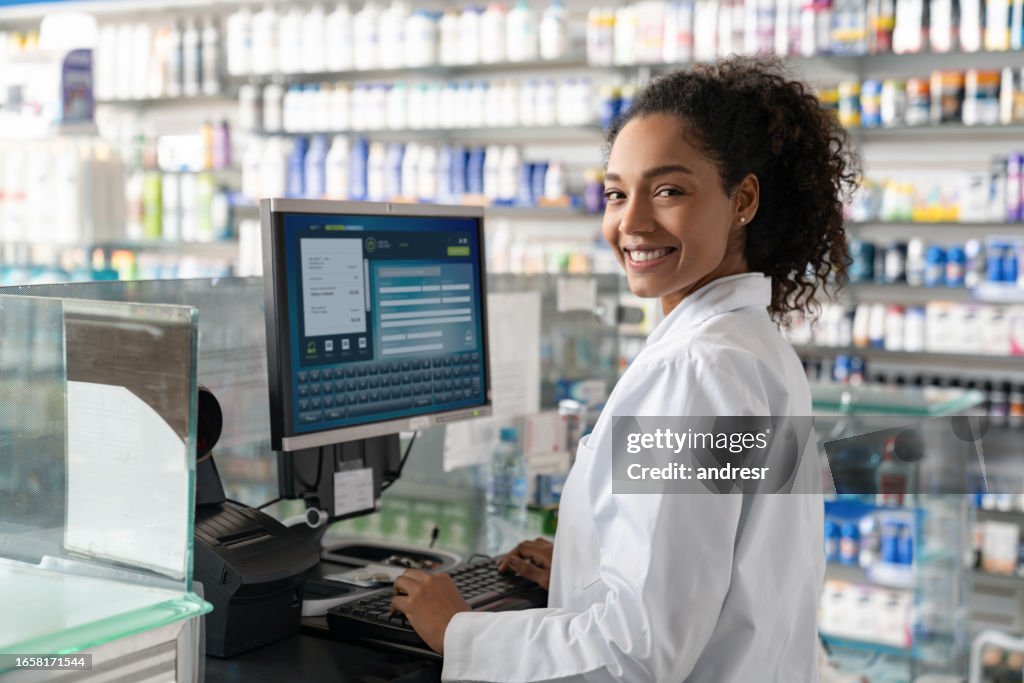 Pharmacist Using A Computer Happy Pharmacist Using The Computer While Working At The Drugstore High ...