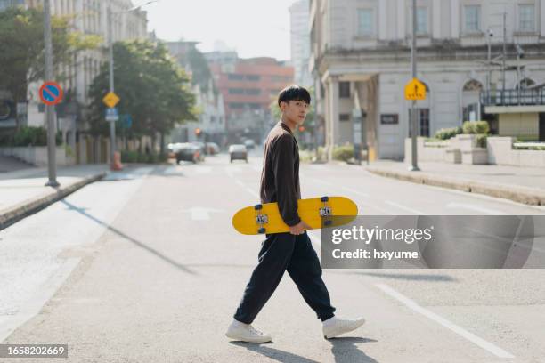 young asian skateboarder walking on the street - street fashion asian stock pictures, royalty-free photos & images