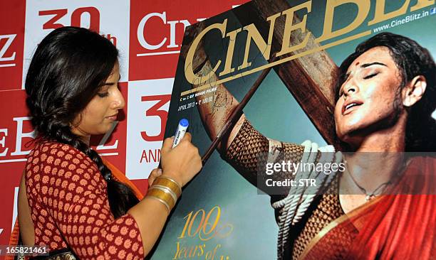 Indian Bollywood film actress Vidya Balan signs a poster of the Cine Blitz cover featuring herself as "Mother India" during the unveiling of the 39th...