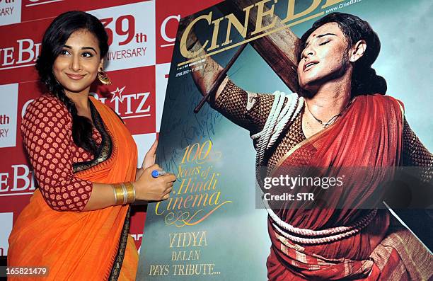 Indian Bollywood film actress Vidya Balan signs a poster of the Cine Blitz cover featuring herself as "Mother India" during the unveiling of the 39th...