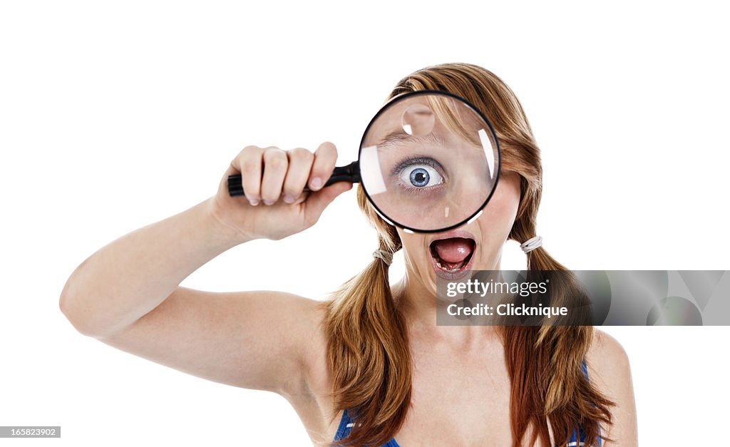 Mujer adolescente sosteniendo una lupa para el ojo