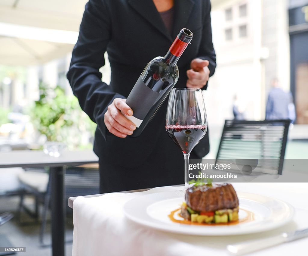 Kellnerin gießen Wein im Glas