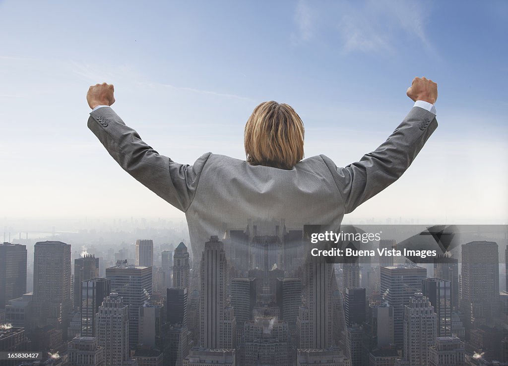 Businessman exulting lifting his arms over a city