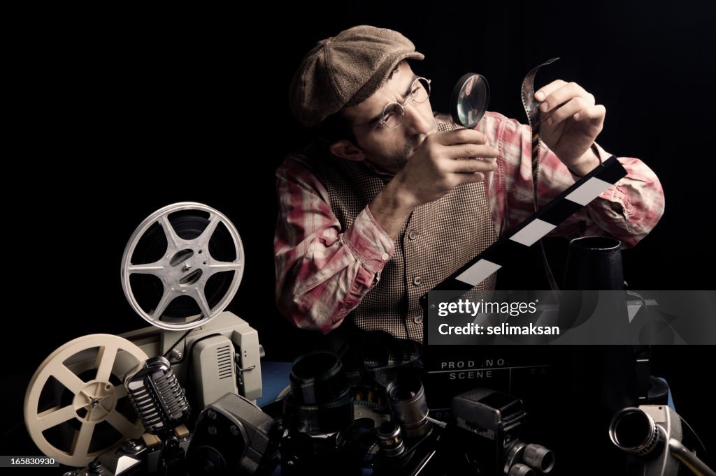 Adulto uomo che tiene un Cinema Film e il controllo con la lente d'ingrandimento
