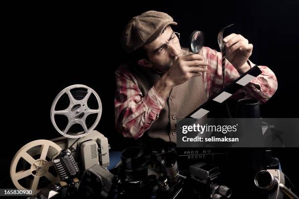 adult man holding cinema film and checking with magnifying glass - you're next 2011 film stock pictures, royalty-free photos & images