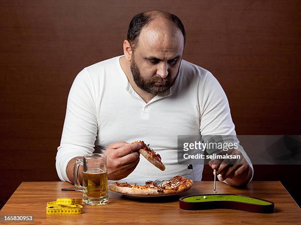 übergewichtige mann essen pizza und tun lazy sport - unangenehmer geschmack stock-fotos und bilder