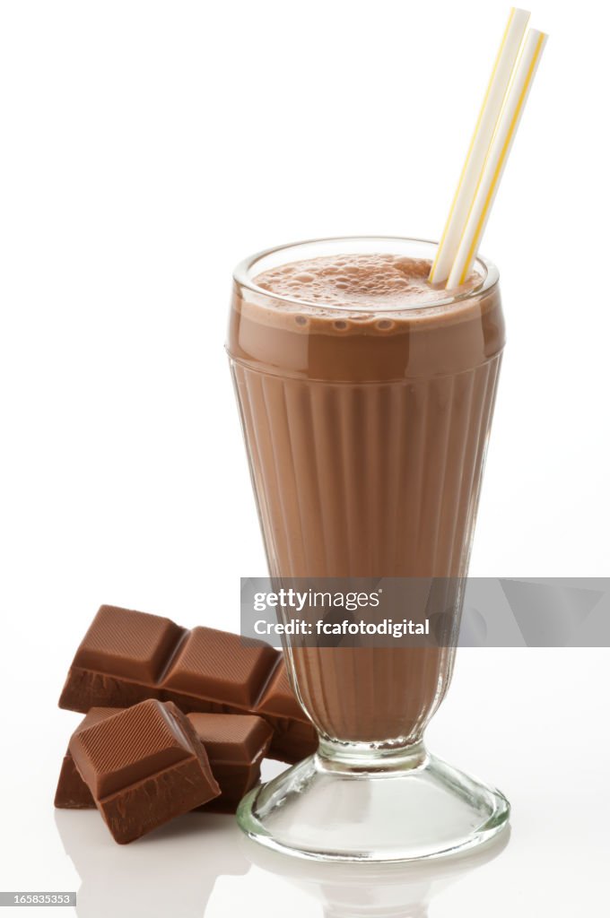 Glass of chocolate milkshake with chocolate chunks on white