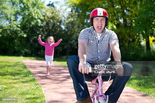 dad riding solo - adult riding bike through park stockfoto's en -beelden