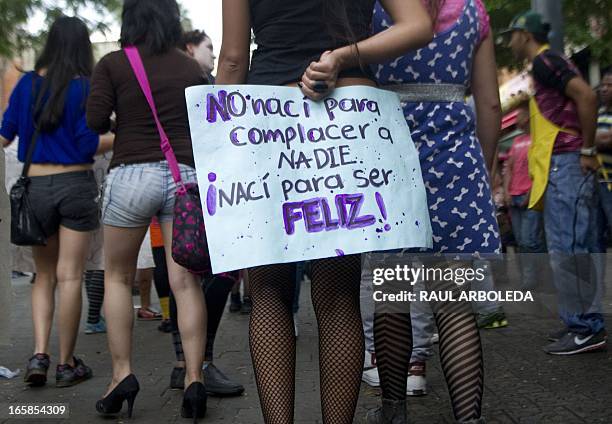 Women hold a sign reading "I wasn't born to please anybody. I was born to be happy!" as they attend the "Putas" march in the streets of Medellin,...