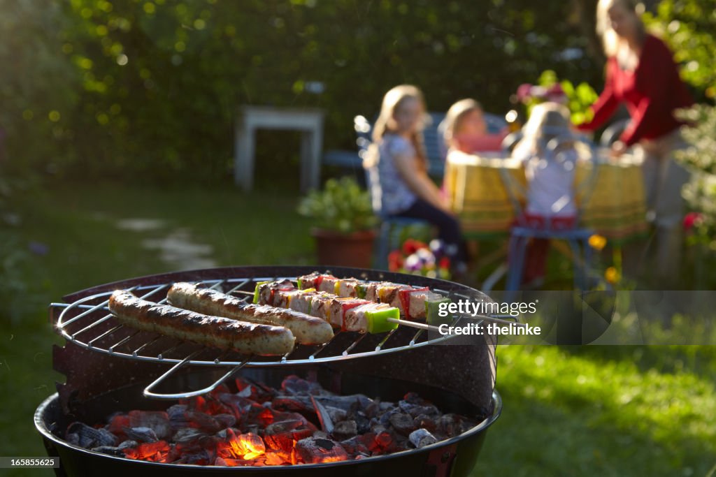 Barbecue grill on a summer evening with family in background