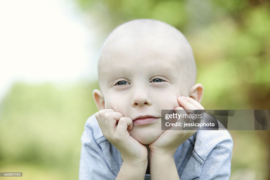 A close up of a young cancer patient daydreaming outside