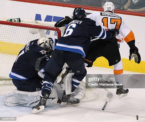 Ondrej Pavelec of the Winnipeg Jets loses his stick as teammate Ron Hainsey shoves Wayne Simmonds of the Philadelphia Flyers past the goal during...
