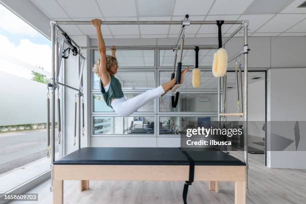 pilates-studio-gym: instruktor am trapeztisch - trapezstange stock-fotos und bilder