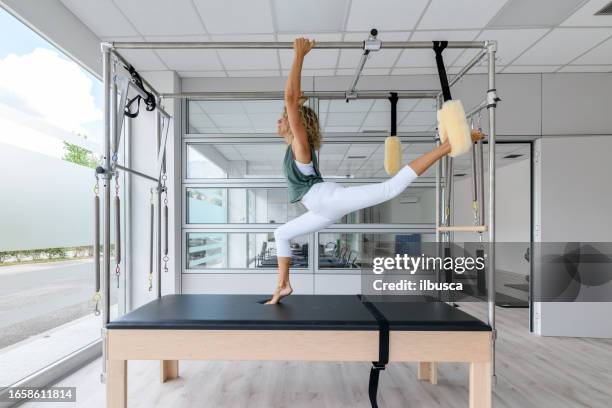 pilates-studio-gym: instruktor am trapeztisch - trapezstange stock-fotos und bilder