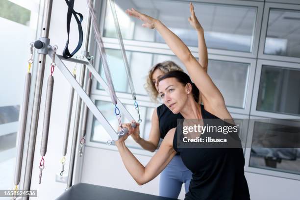 pilates-studio-fitnessstudio: frau mit trapez-tischmaschine - trapezstange stock-fotos und bilder