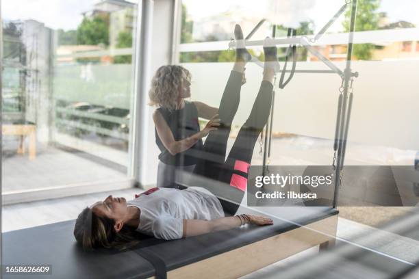 pilates-studio-fitnessstudio: frau mit trapez-tischmaschine - trapezstange stock-fotos und bilder