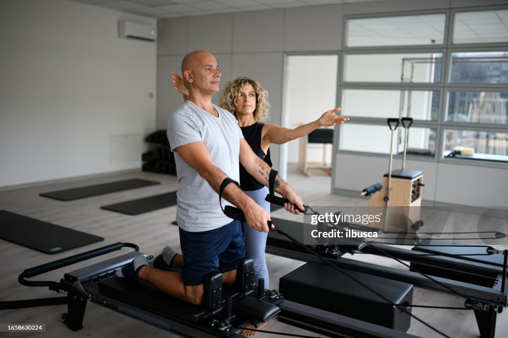 Pilates studio gym: Man using reformer