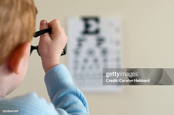 young boy reading from eye chart - eye test chart stock pictures, royalty-free photos & images