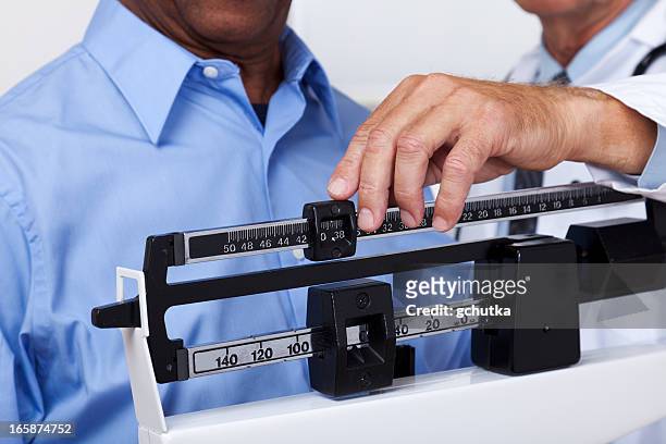 doctor checking weight - weighing scales stockfoto's en -beelden