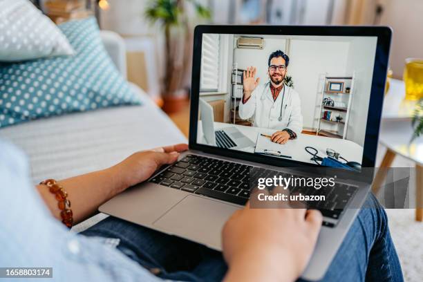 young woman having a doctor's appointment online at home - telemedicine stock pictures, royalty-free photos & images