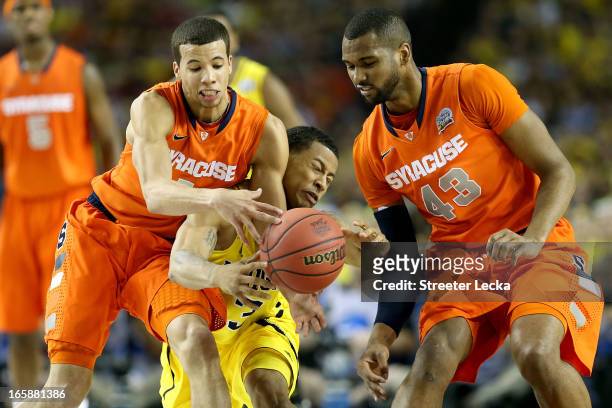 Trey Burke of the Michigan Wolverines attempts to control the ball in the first half against Michael Carter-Williams and James Southerland of the...