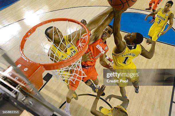 Michael Carter-Williams of the Syracuse Orange drives to the basket against Jordan Morgan and Glenn Robinson III of the Michigan Wolverines during...