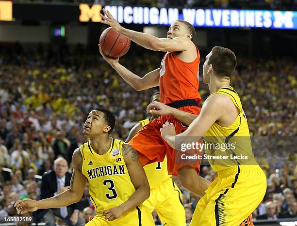 Brandon Triche of the Syracuse Orange drives for a shot attempt in the secodn half against Trey Burke and Mitch McGary of the Michigan Wolverines...