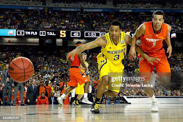 Trey Burke of the Michigan Wolverines reaches for the ball in the first half against Michael Carter-Williams of the Syracuse Orange during the 2013...