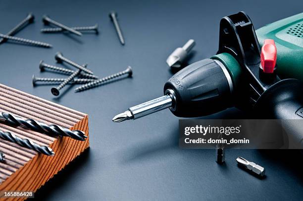 electric drill with drill bits, screws on dark background - elektrisch gereedschap stockfoto's en -beelden
