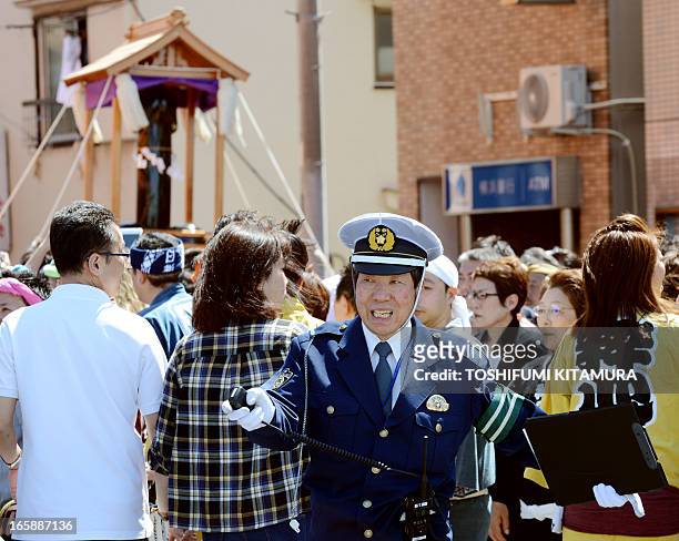 Police officer controls the crowds beside a phallus-shaped portable shrine during the Kanamara festival near the Kanayama shrine in Kawasaki,...