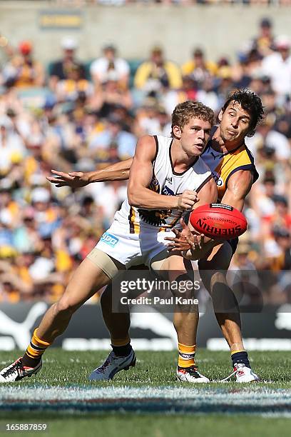 Jed Anderson of the Hawks handballs against Andrew Embley of the Eagles during the round two AFL match between the West Coast Eagles and the Hawthorn...