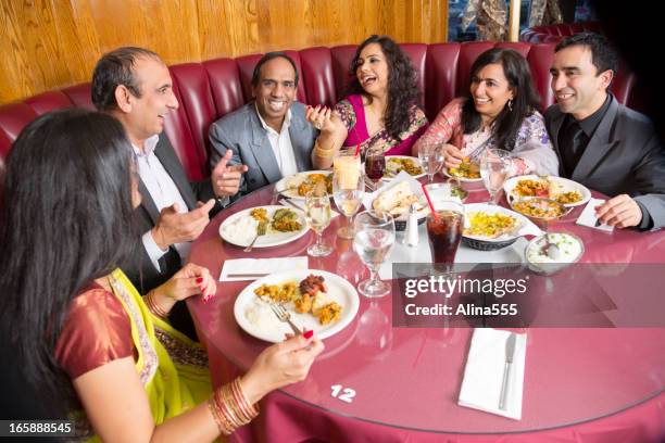 happy group of adult friends at an indian restaurant - indian restaurant stock pictures, royalty-free photos & images