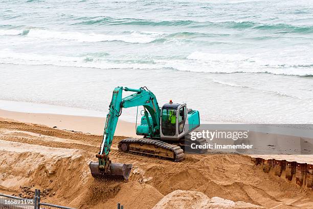 excavator working on the beach with ocean, copy space - beach shovel stockfoto's en -beelden