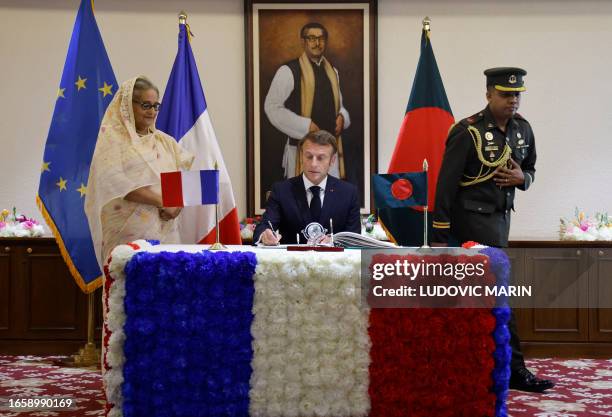 France's President Emmanuel Macron signs a gold book upon his arrival at Bangladesh's Prime Minister Sheikh Hasina's office in Dhaka on September 11,...