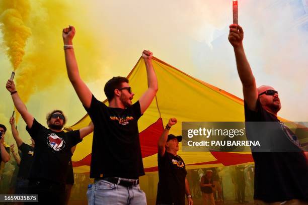 Members of FC Barcelona suporters group Dracs 1991 sing the Catalonia's anthem as they hold torch and a Catalan pro-independence "Estelada" flag...