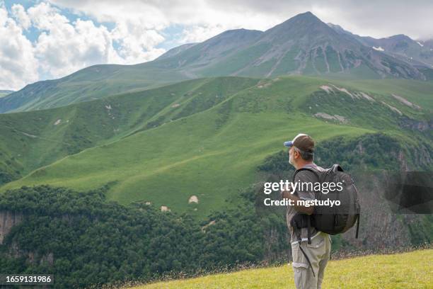 mature man watching the caucasus mountains view on a sunny day kazbegi,georgia - caucasus stock pictures, royalty-free photos & images